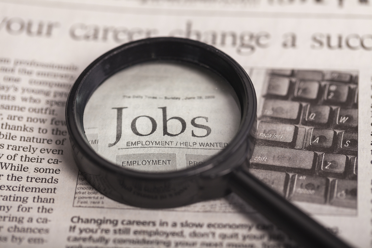 Magnifying glass on top of newspaper job ads