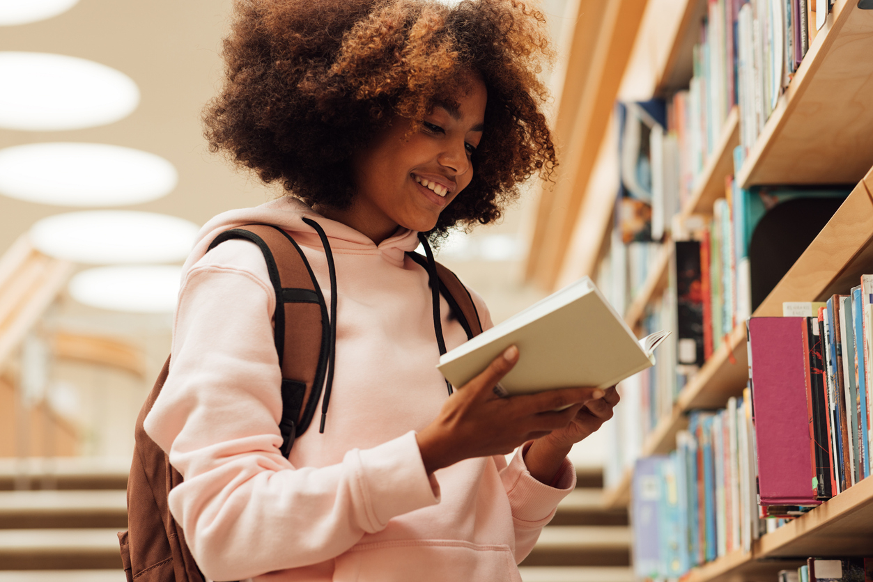 Student in library reading book.